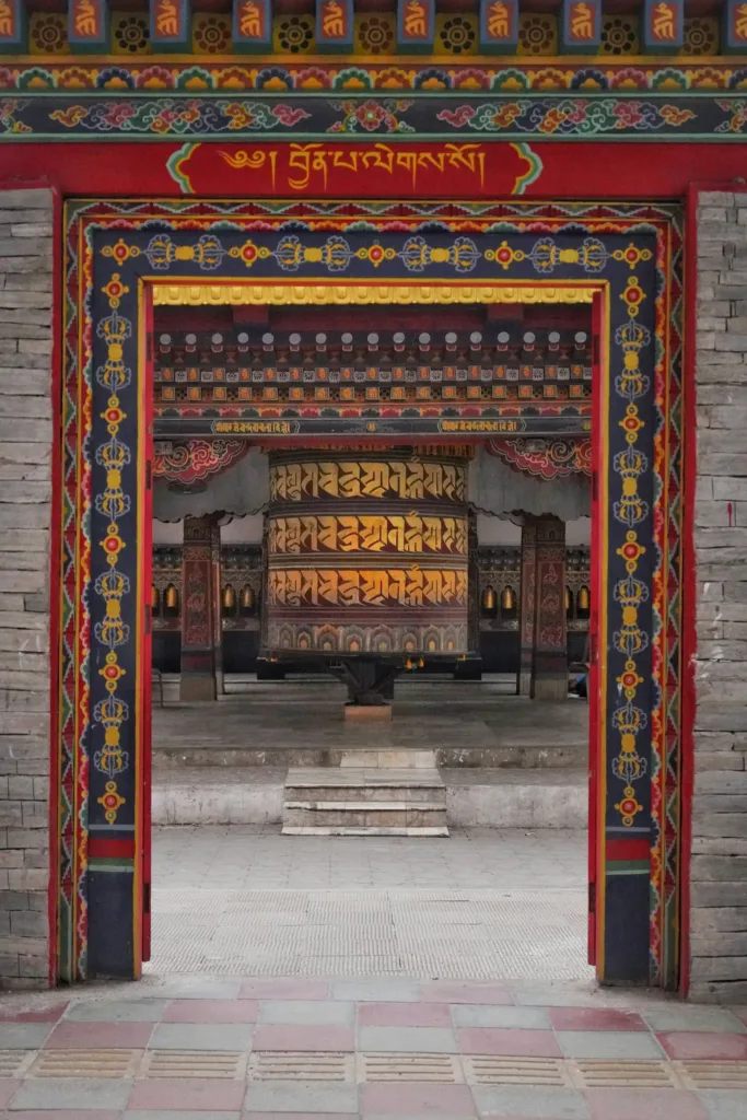 Velký zdobený modlitební mlýn za barevným vstupem do tibetského buddhistického chrámu.