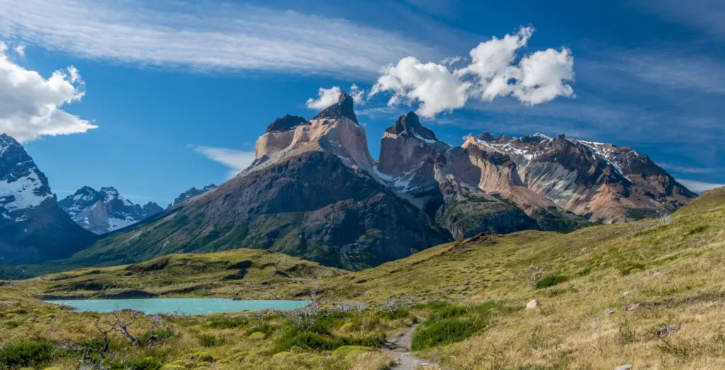 Skalnaté vrcholy Cuernos del Paine nad travnatou patagonskou krajinou a malým jezírkem