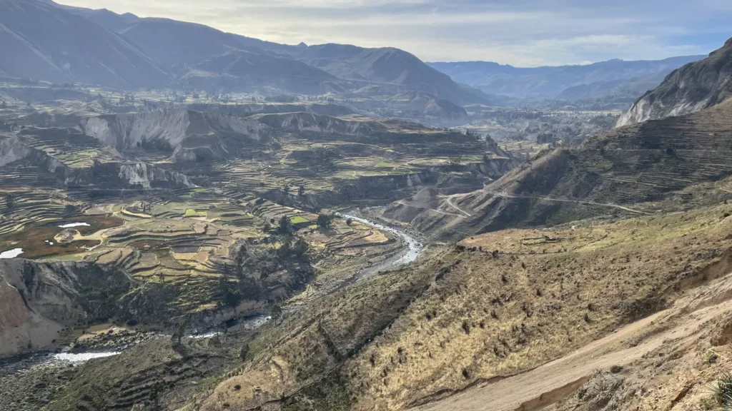 Pohled do horského údolí kaňonu Colca s terasovitými poli a řekou mezi suchými svahy