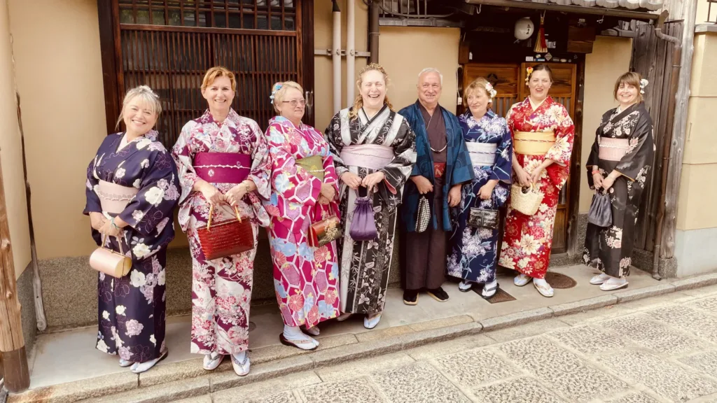 Skupina turistů v barevných kimonech stojí v úzké tradiční uličce v Japonsku.