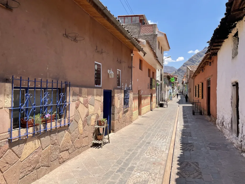 Úzká dlážděná ulice s barevnými domy a horskými svahy v Ollantaytambu v Peru