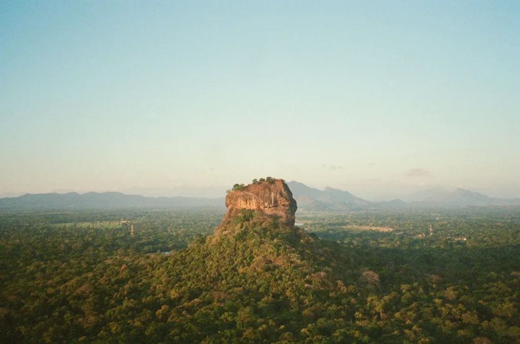 Monumentální skalní útvar Sigiriya vystupující nad zelenou tropickou krajinou.