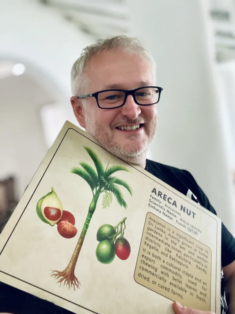 Usmívající se muž drží ilustraci palmy arekového ořechu s plody.