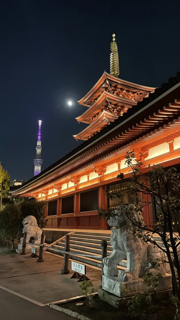 Noční pohled na osvětlený chrám Sensó-dži s pětipatrovou pagodou a věží Tokyo Skytree v pozadí.