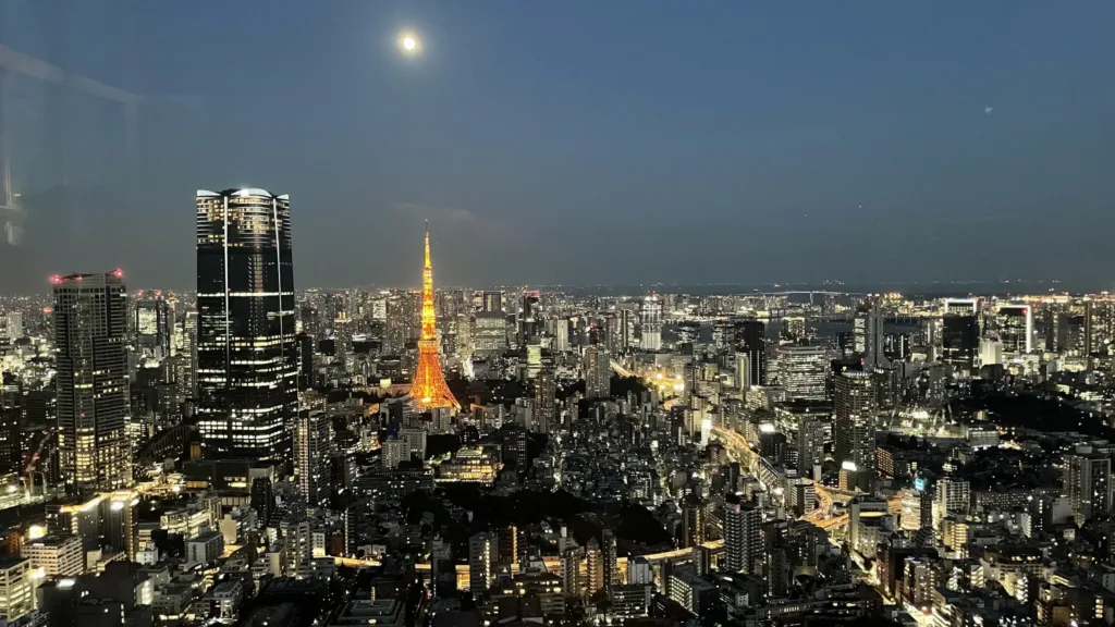 Noční panorama Tokia s osvětlenou věží Tokyo Tower a měsícem nad městem