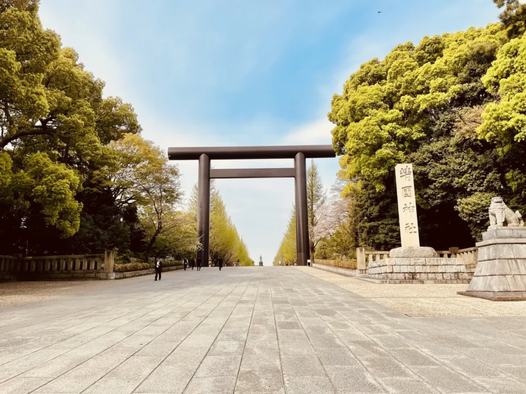 Velká brána torii na široké cestě lemované stromy u svatyně Jasukuni v Tokiu.