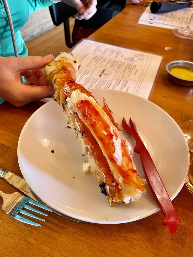 Host drží otevřenou polovinu humra nad talířem v restauraci.