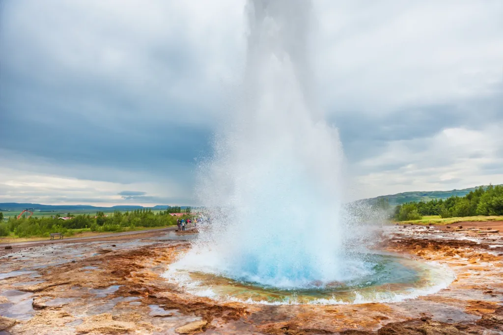 Erupce gejzíru Strokkur s vysokým sloupcem vody v geotermální oblasti na Islandu.