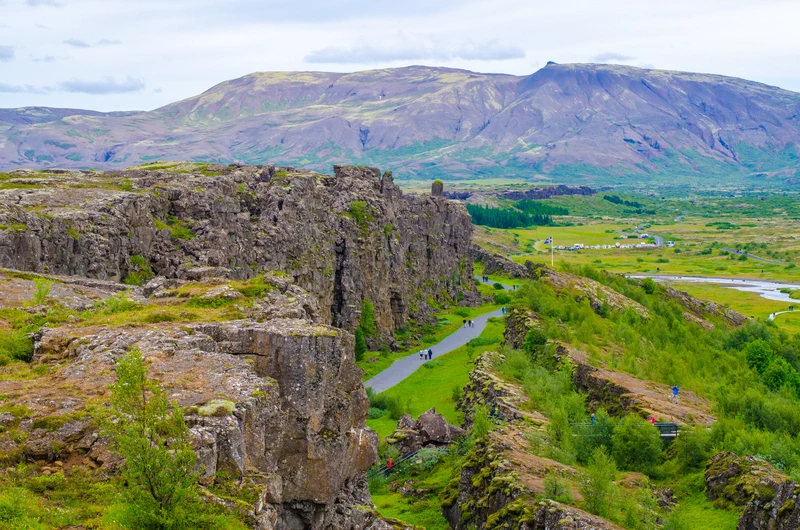 Skalní stěny tektonické trhliny Almannagjá s pěší stezkou v národním parku Þingvellir na Islandu