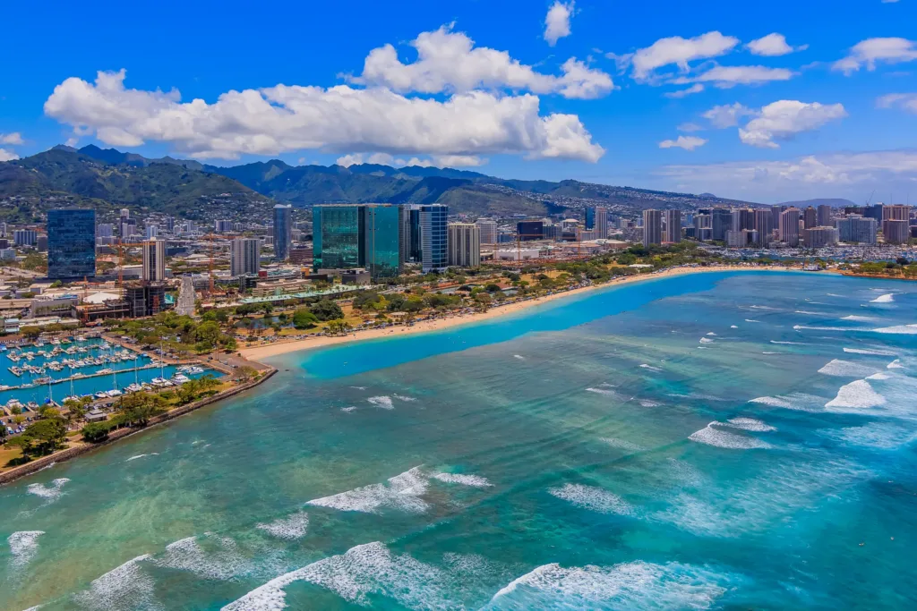 Letecký pohled na tyrkysové moře, pláž Ala Moana a moderní zástavbu Honolulu na ostrově Oahu.