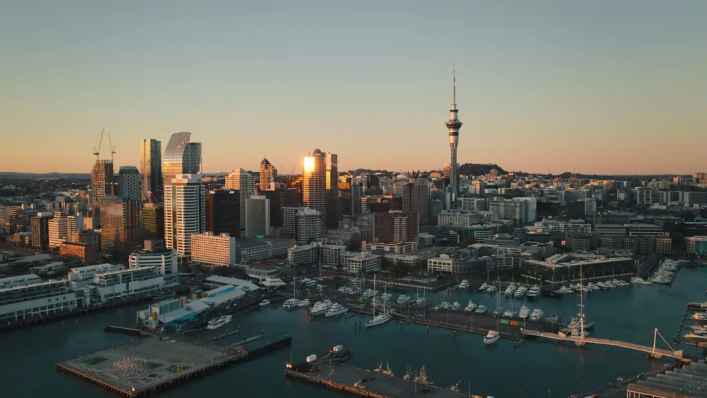 Letecký pohled na panorama Aucklandu se Sky Tower a přístavní marinou při západu slunce