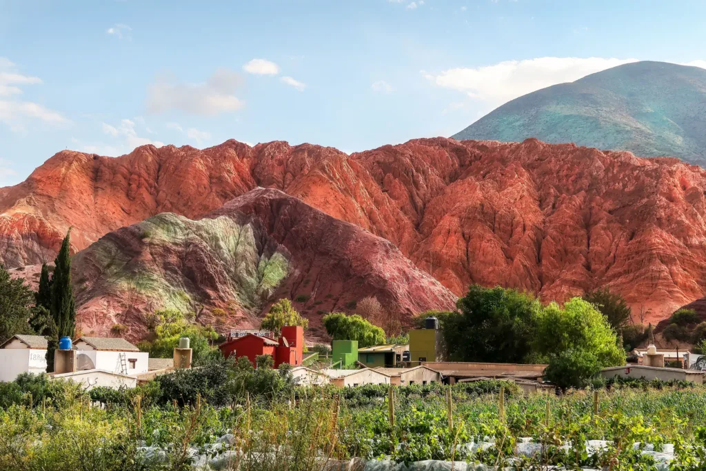 Barevné vrstevnaté svahy hory Cerro de los Siete Colores nad domy a zelení v Purmamarce.