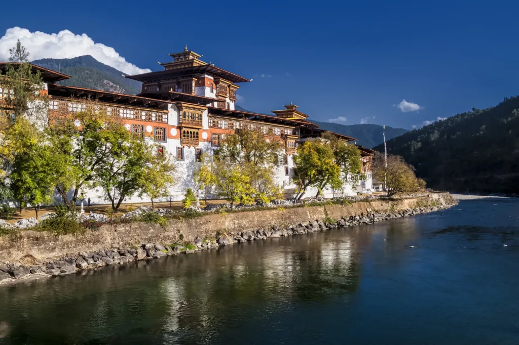 Punakha Dzong, tradiční bhútánský klášterní komplex na břehu řeky mezi zalesněnými horami