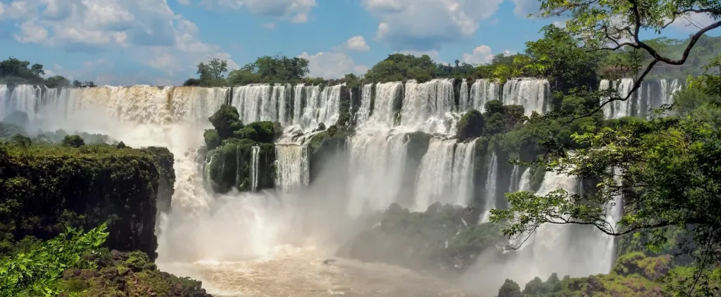Široké kaskády vodopádů Iguazú obklopené tropickou zelení a vodní tříští.