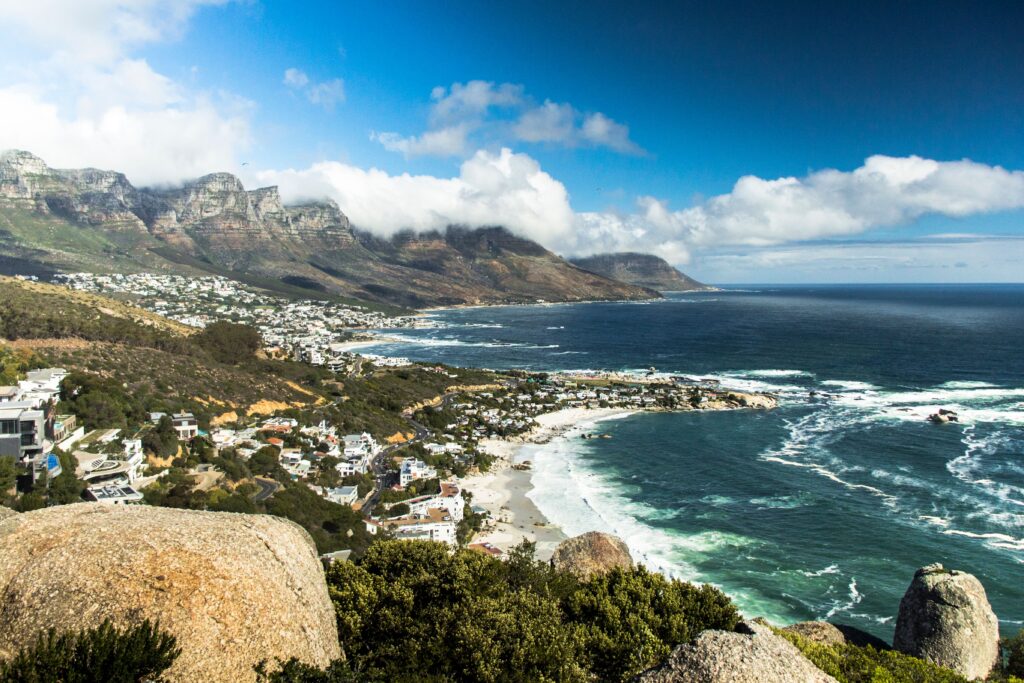 Pohled z vyhlídky na zástavbu Camps Bay, skalnaté pobřeží Atlantského oceánu a hory Twelve Apostles v Kapském Městě.