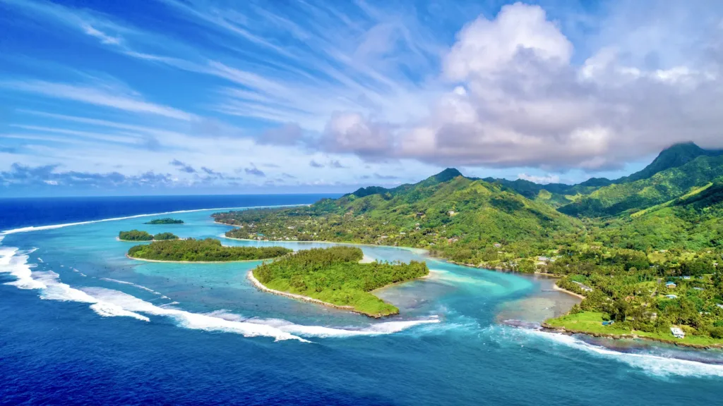 Letecký pohled na tyrkysovou lagunu, korálový útes a zelené horské pobřeží ostrova Rarotonga.