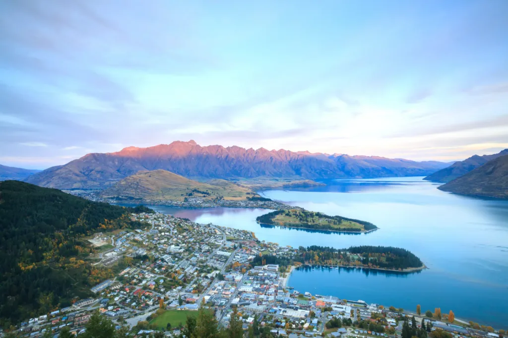 Letecký pohled na město Queenstown na Novém Zélandu obklopené horami a jezerem Wakatipu za soumraku