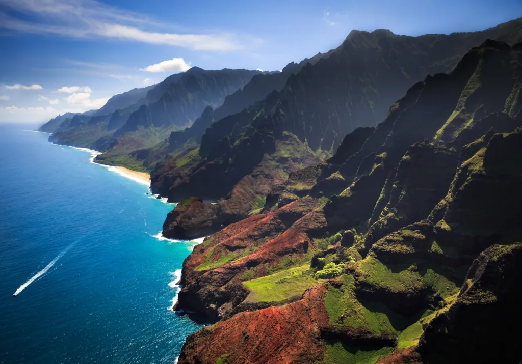 Letecký pohled na strmé zelené útesy pobřeží Nā Pali a tyrkysový oceán na ostrově Kauai