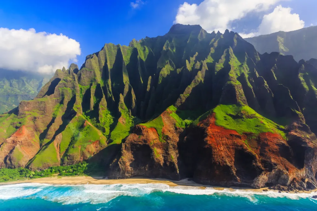 Strmé zelené útesy pobřeží Nā Pali na ostrově Kauai nad tyrkysovým oceánem