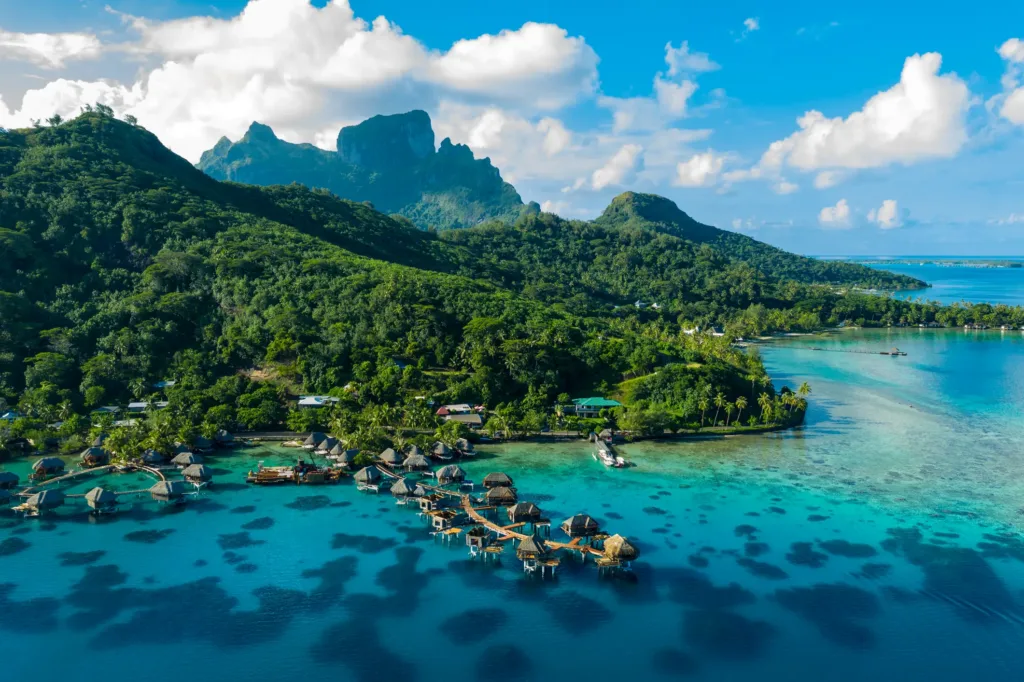 Tyrkysová laguna s bungalovy nad vodou a zelené horské vrcholy ostrova Bora Bora