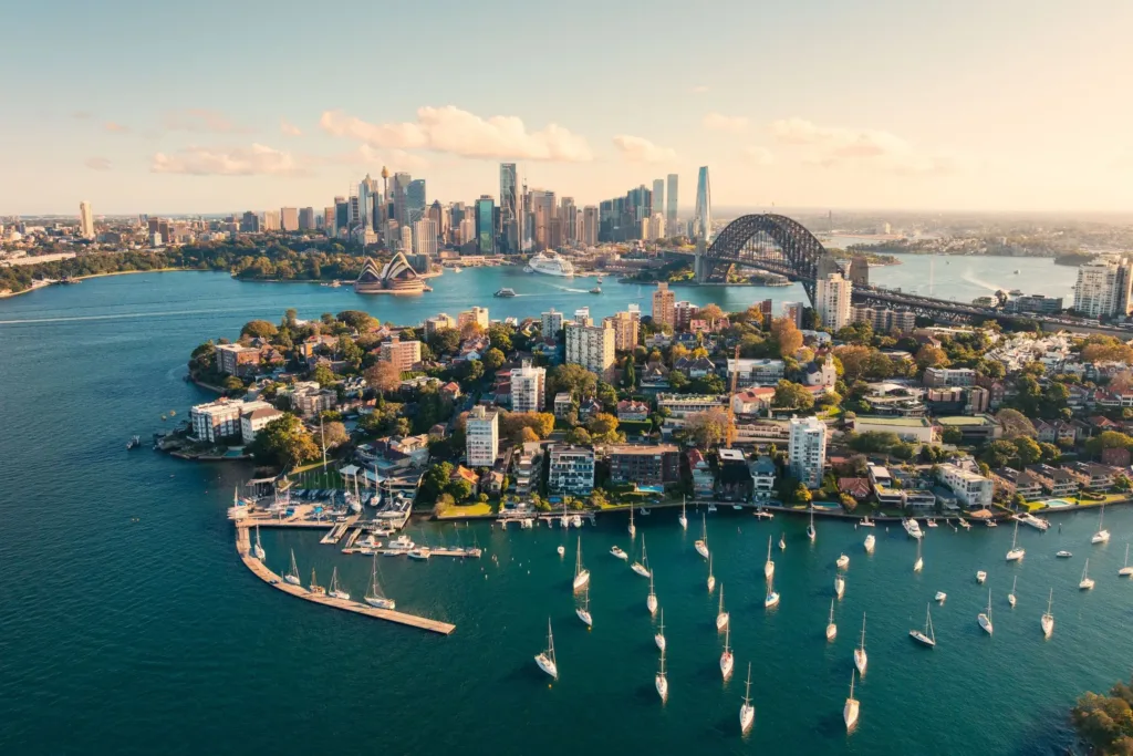 Letecký pohled na záliv v Sydney s kotvícími plachetnicemi, mrakodrapy a mostem Sydney Harbour Bridge