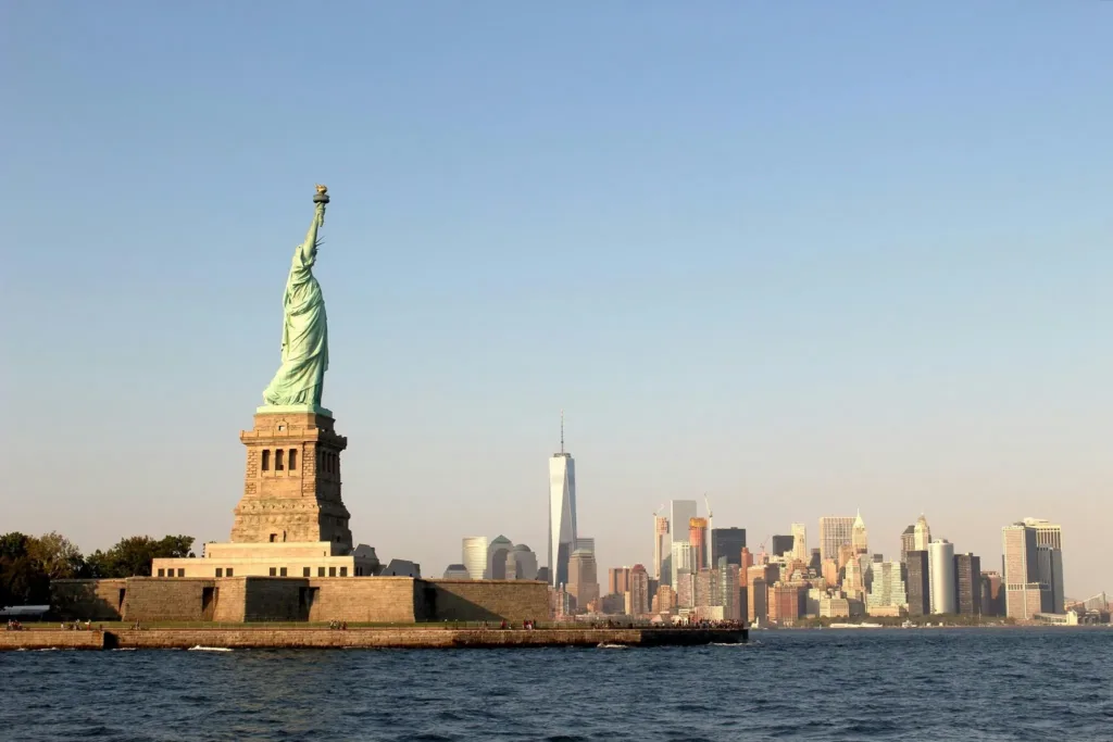 Socha Svobody na ostrově v záhlaví Hudsonova zálivu s mrakodrapy dolního Manhattanu a věží One World Trade Center v pozadí