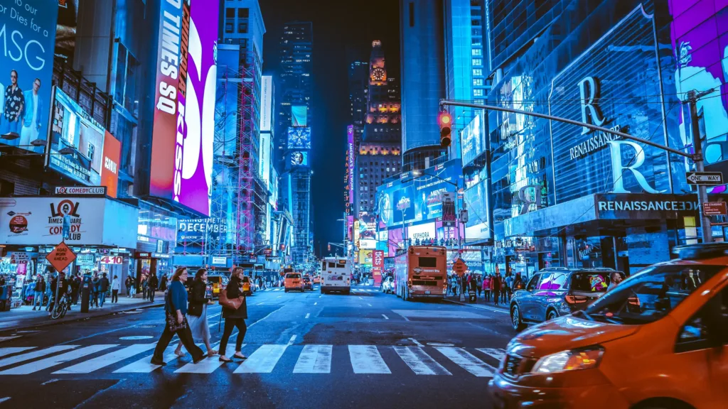 Rušná noční ulice s neonovými reklamami, přechodem pro chodce, taxíky a chodci na Times Square v New Yorku